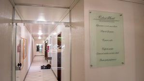 Un pasillo de hotel con una puerta de cristal, y un cartel que enumera servicios como piscina, desayuno e internet.