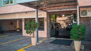 Entrada de un hotel con área de estacionamiento techada, número de entrada visible y cámara de seguridad.