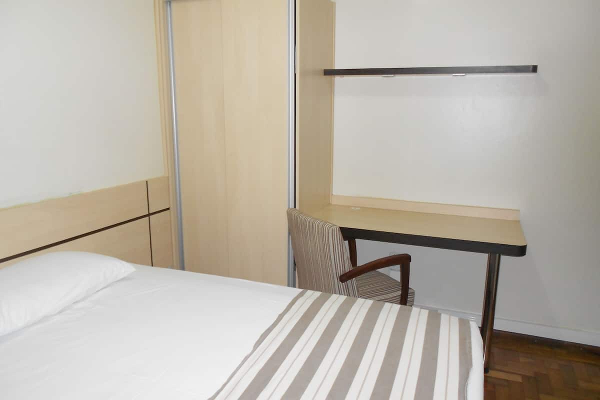 A hotel room with a bed, a desk, and a chair.