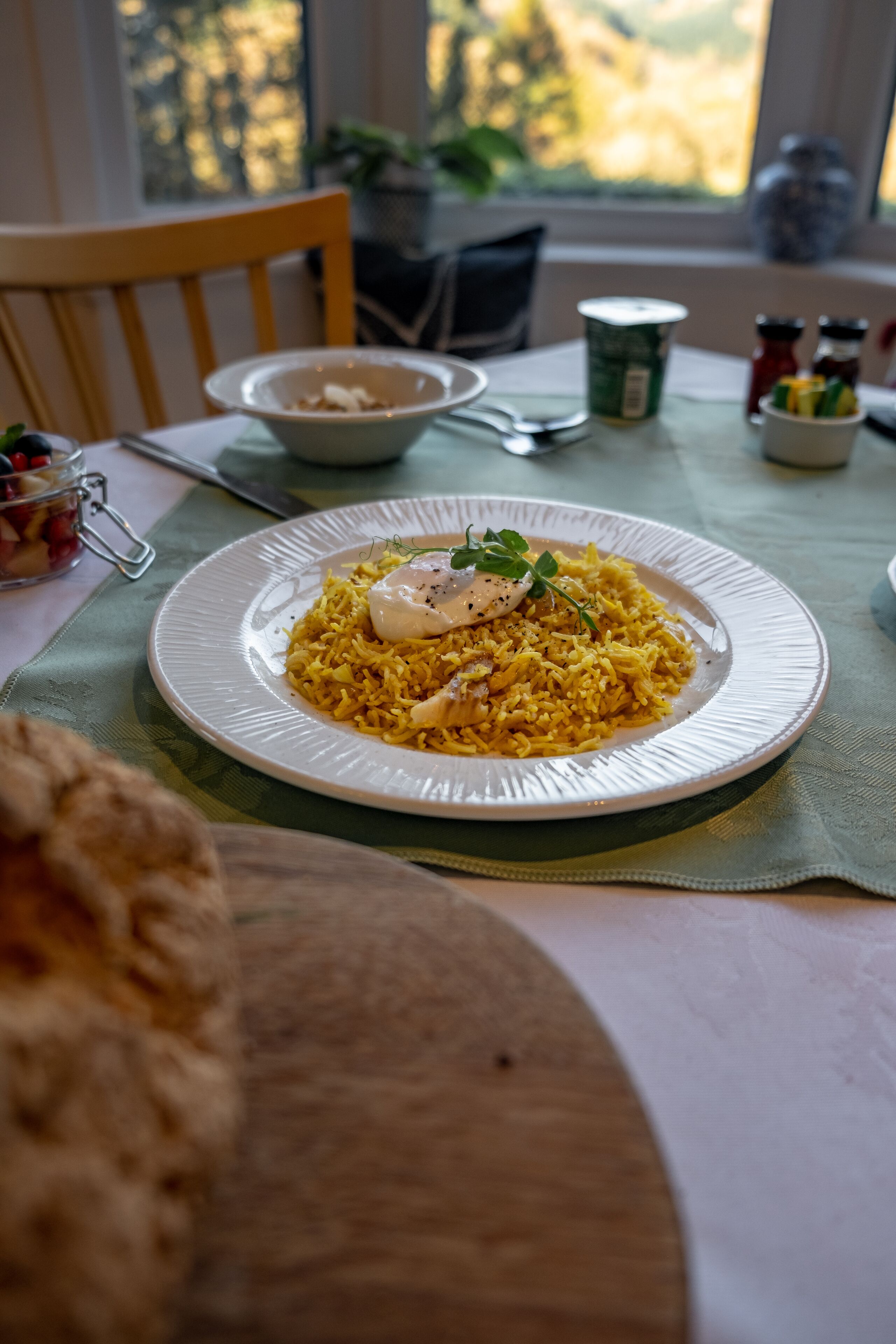 A dining table with a plate of food, a bowl, and some condiments.