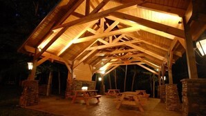 Un espace extérieur abrité, doté de tables de pique-nique en bois et de piliers en pierre.