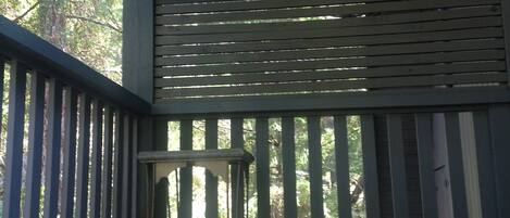 Um deck de madeira com uma placa de 'Welcome', um vaso suspenso e um guarda-corpo de metal.
