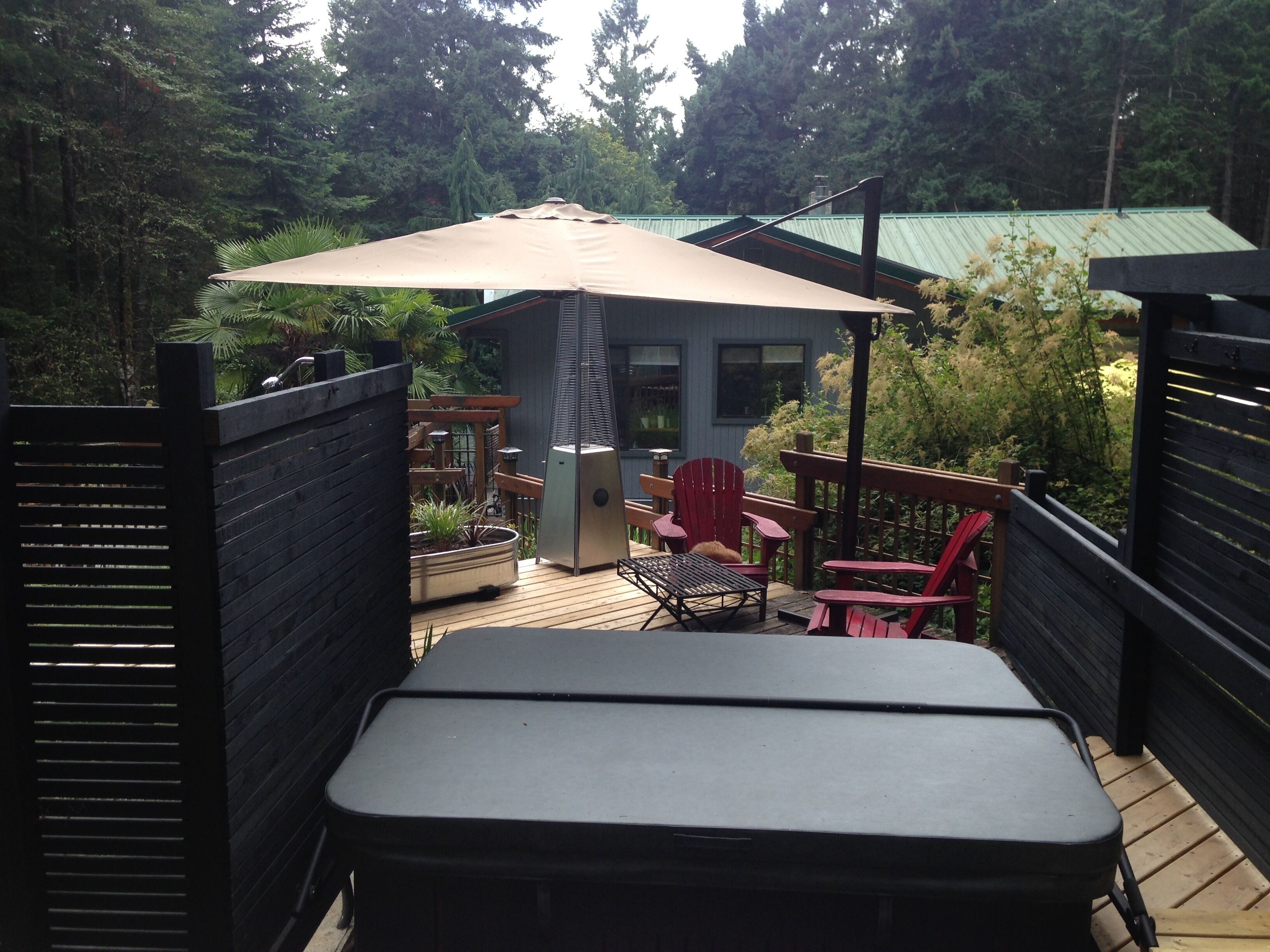 A deck with a table and chairs, a patio umbrella, and a small building with windows.