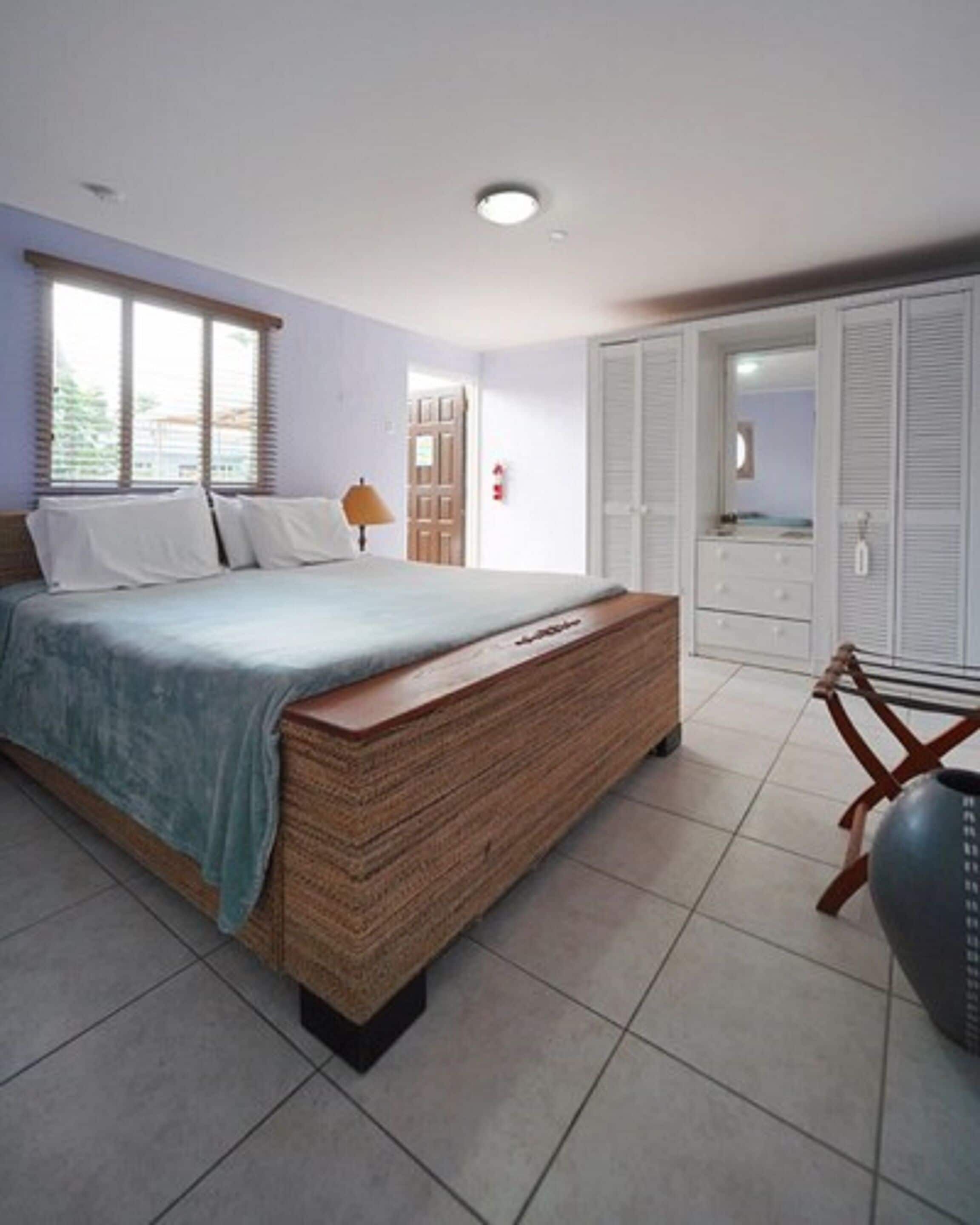 Une chambre à coucher avec un lit, une table de chevet, une lampe, une armoire et un miroir.