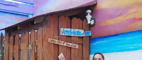 Ein Holzzaun mit Schildern, auf denen 'Aruba Inn' und 'Little Slice of Paradise' stehen.