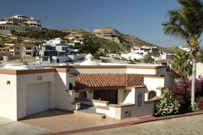 A residential building with a tiled roof, a garage, and a small garden with flowers. - Casa de Amor (Cabo San Lucas)