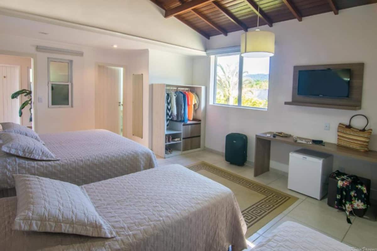 A bedroom with two beds, a TV, a desk, and a wardrobe.