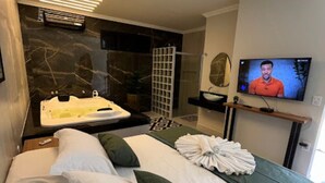 A modern hotel room with a large bed, a TV, a bathtub, and a shower area.