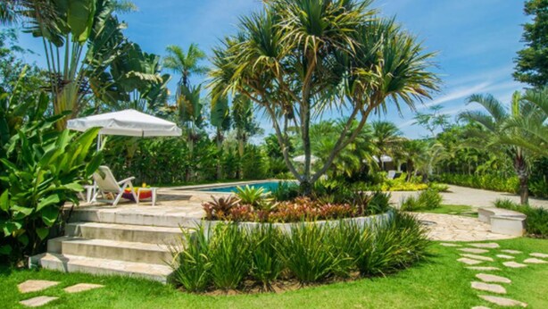A well-maintained garden with a pool, outdoor seating, and a variety of tropical plants.