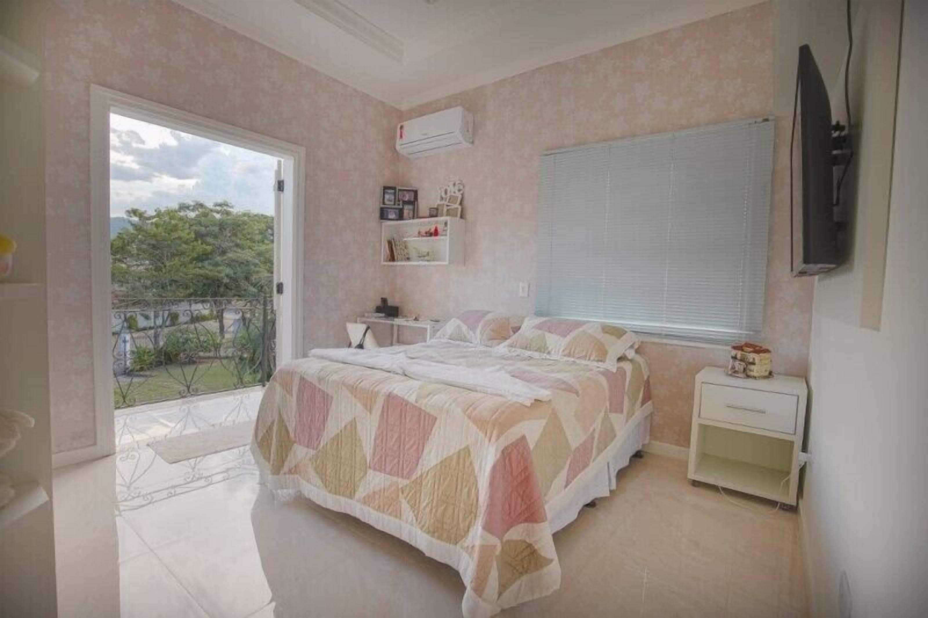 A bedroom with a bed, a nightstand, a TV, and a window.