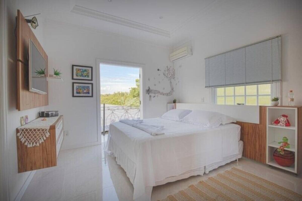 A bedroom with a bed, a desk, a window, and a door leading to an outdoor area.