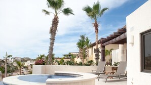 Un área de piscina con jacuzzi, palmeras y asientos al aire libre.