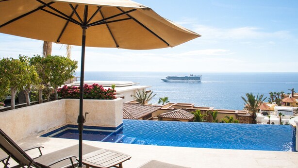 Zona junto a la piscina con vistas al océano y un crucero a lo lejos.