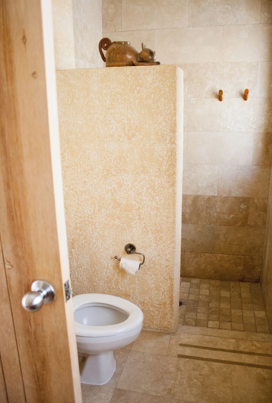A bathroom with a toilet, a towel rack, and a shower area.
