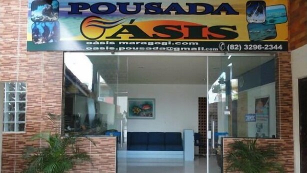 A reception area with a glass door, a blue sofa, and potted plants. - Pousada Residence Oásis (Maragogi)