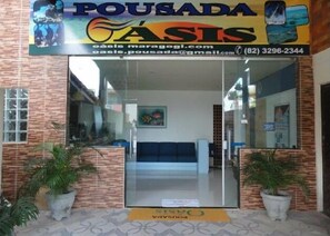 A reception area with a glass door, a blue sofa, and potted plants. - Pousada Residence Oásis (Maragogi)