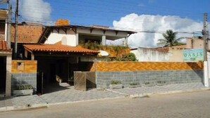A building with a tiled roof, a brick wall, and a sign that reads "OASIS". - Pousada Residence Oásis (Maragogi)