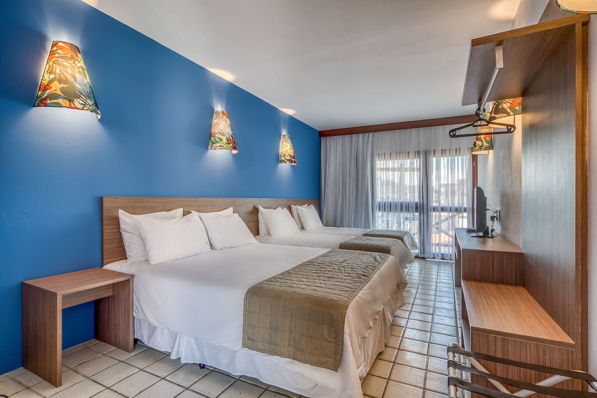 Habitación de hotel con una cama grande, mesitas de noche, un escritorio y vistas al exterior.