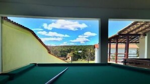 Une table de billard offrant une vue dégagée sur un paysage montagneux grâce à de grandes fenêtres.