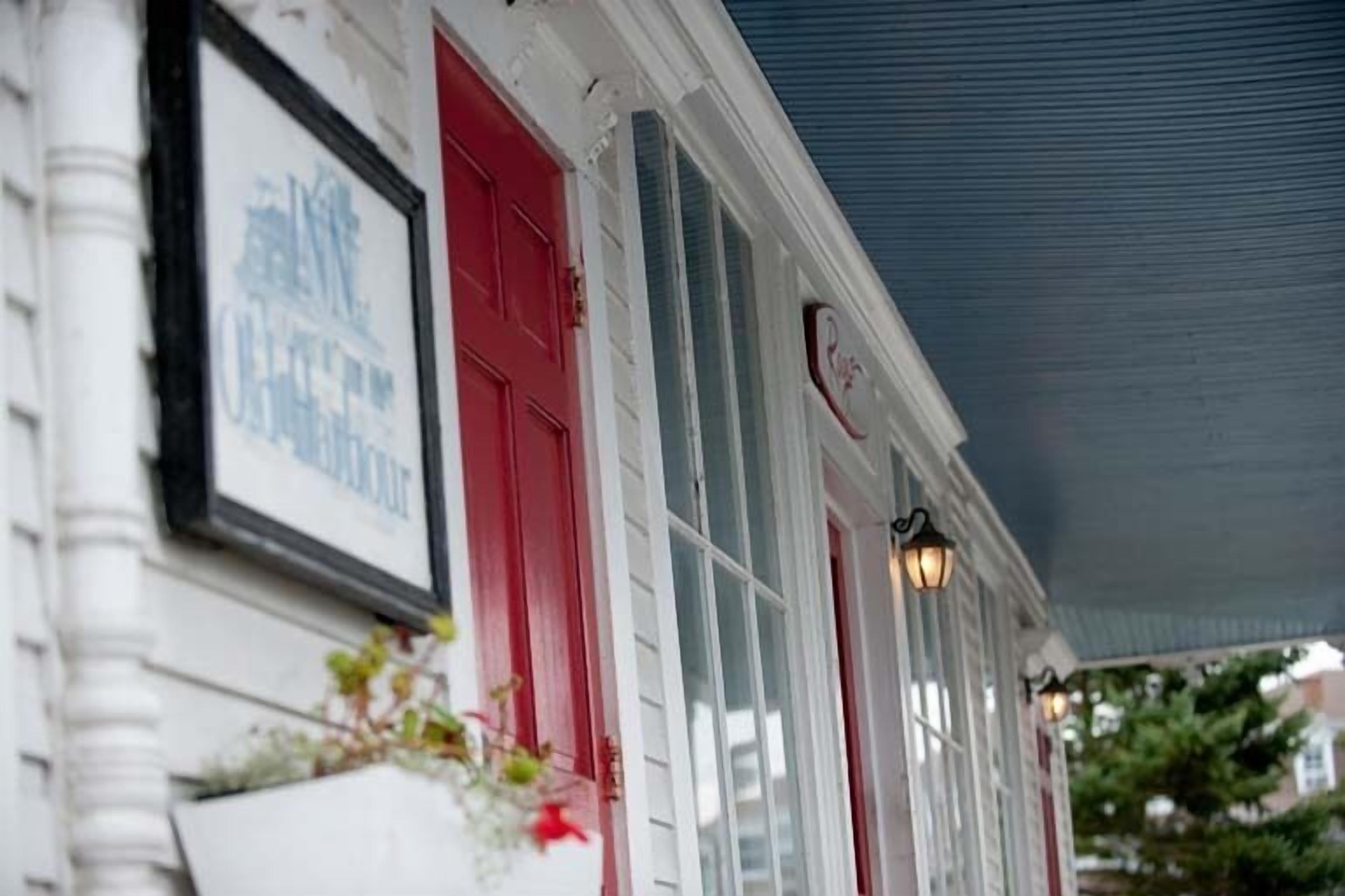 A building facade with a red door, white columns, and a framed sign.