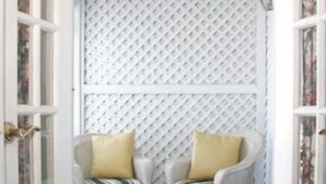 A room with two rocking chairs, a small table, and a patterned wall. - Inn at Old Harbor (Block Island)