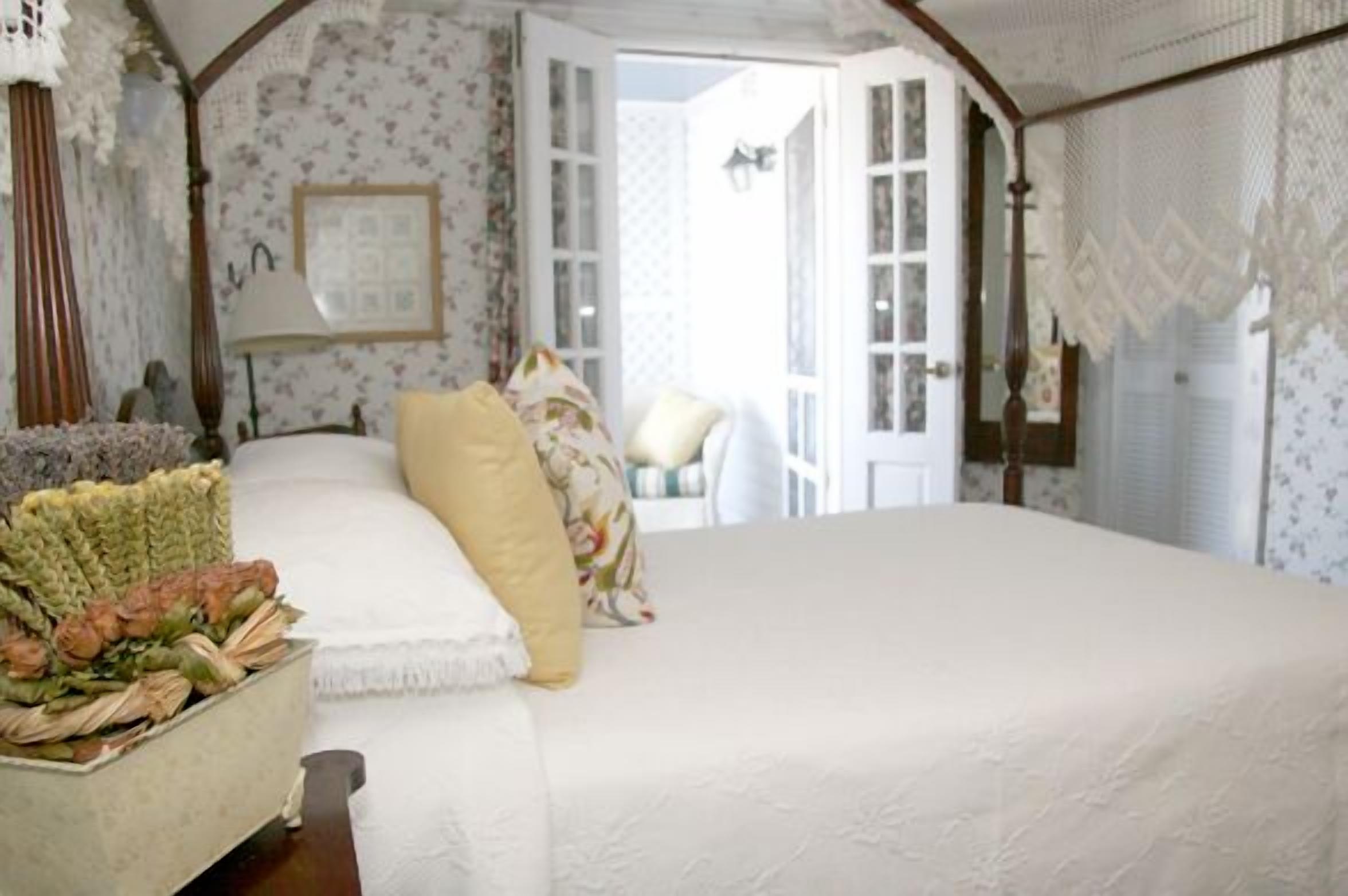 Une chambre avec un grand lit, un papier peint à motifs floraux et une vue sur l’extérieur.