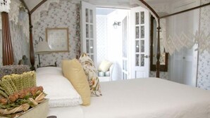 Un dormitorio con una cama grande, papel tapiz con motivos florales y vistas al exterior.