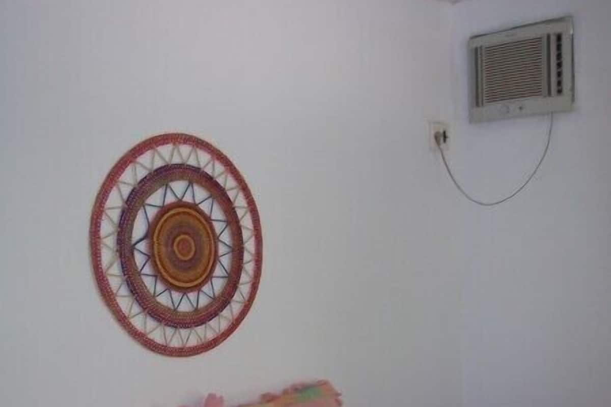 Un lit simple avec une couverture colorée, deux oreillers et une décoration murale.