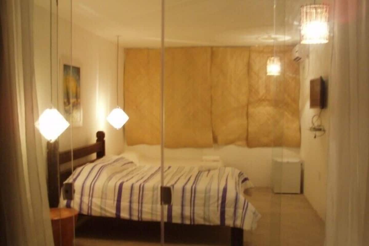 Une chambre d’hôtel équipée d’un lit, de lampes de chevet, d’une table de chevet et d’un téléviseur fixé au mur.
