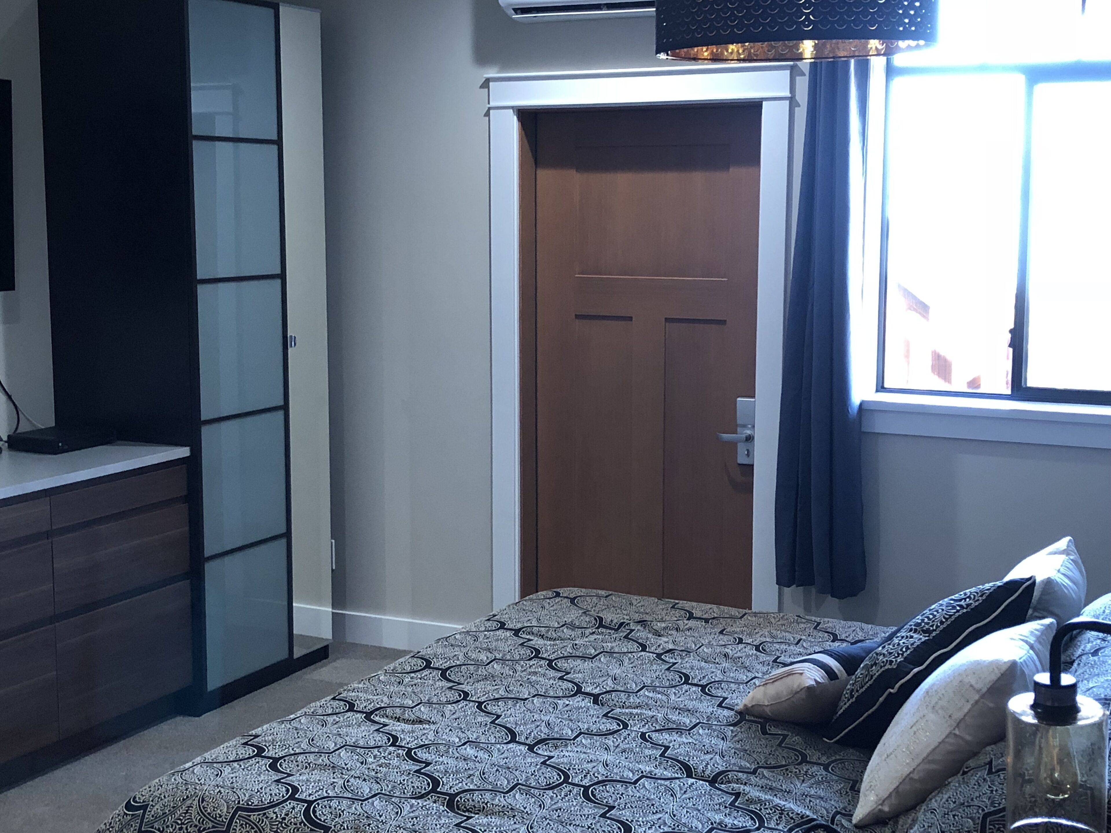 A bedroom with a bed, a wardrobe, a door, and a window.
