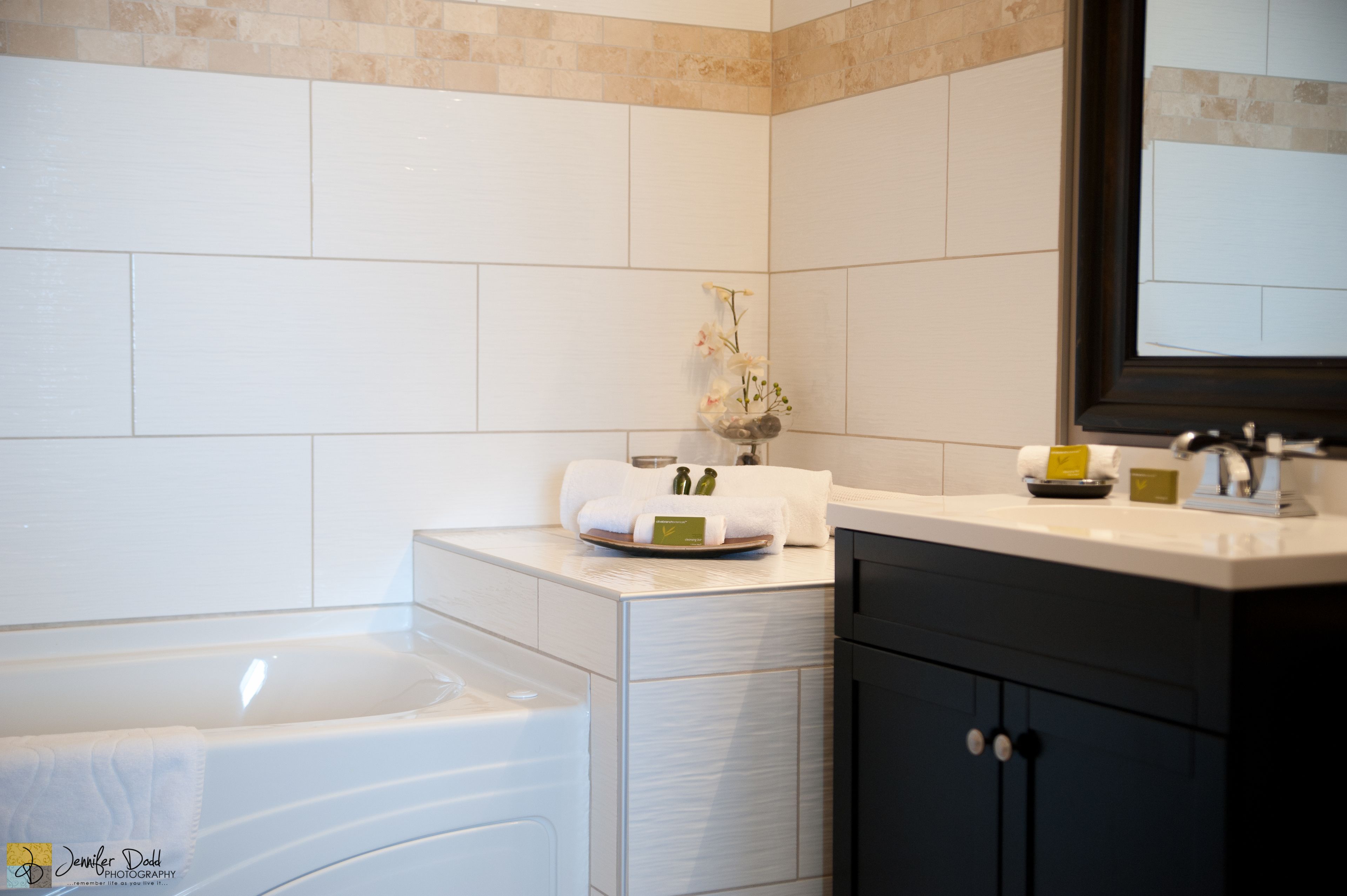 Un baño moderno con bañera, tocador con espejo y un jarrón decorativo en la encimera.
