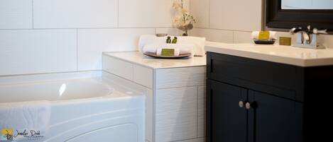 Un baño moderno con bañera, tocador con espejo y un jarrón decorativo en la encimera.