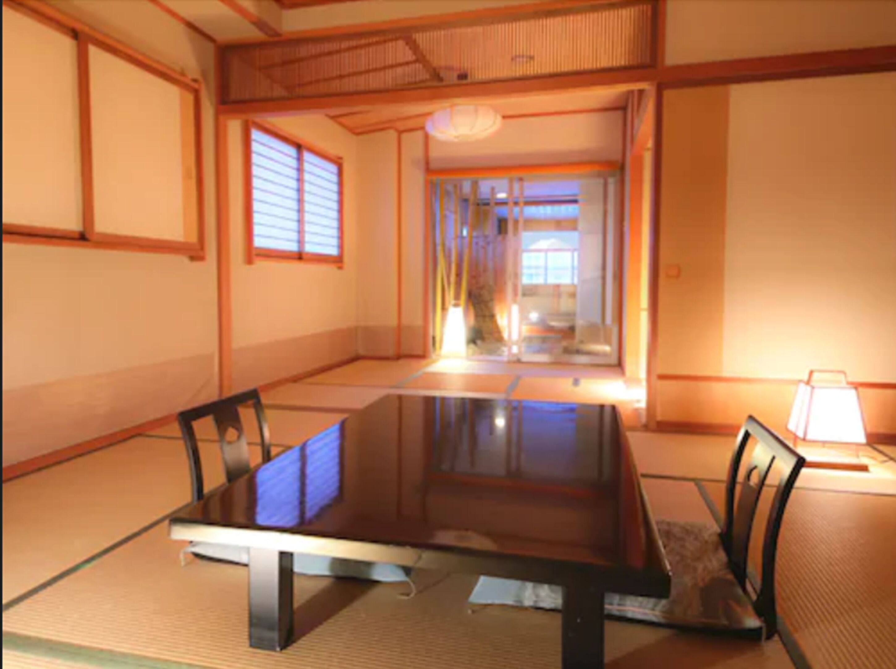 A traditional Japanese tatami room with a low table, tatami mats, and shoji screens.