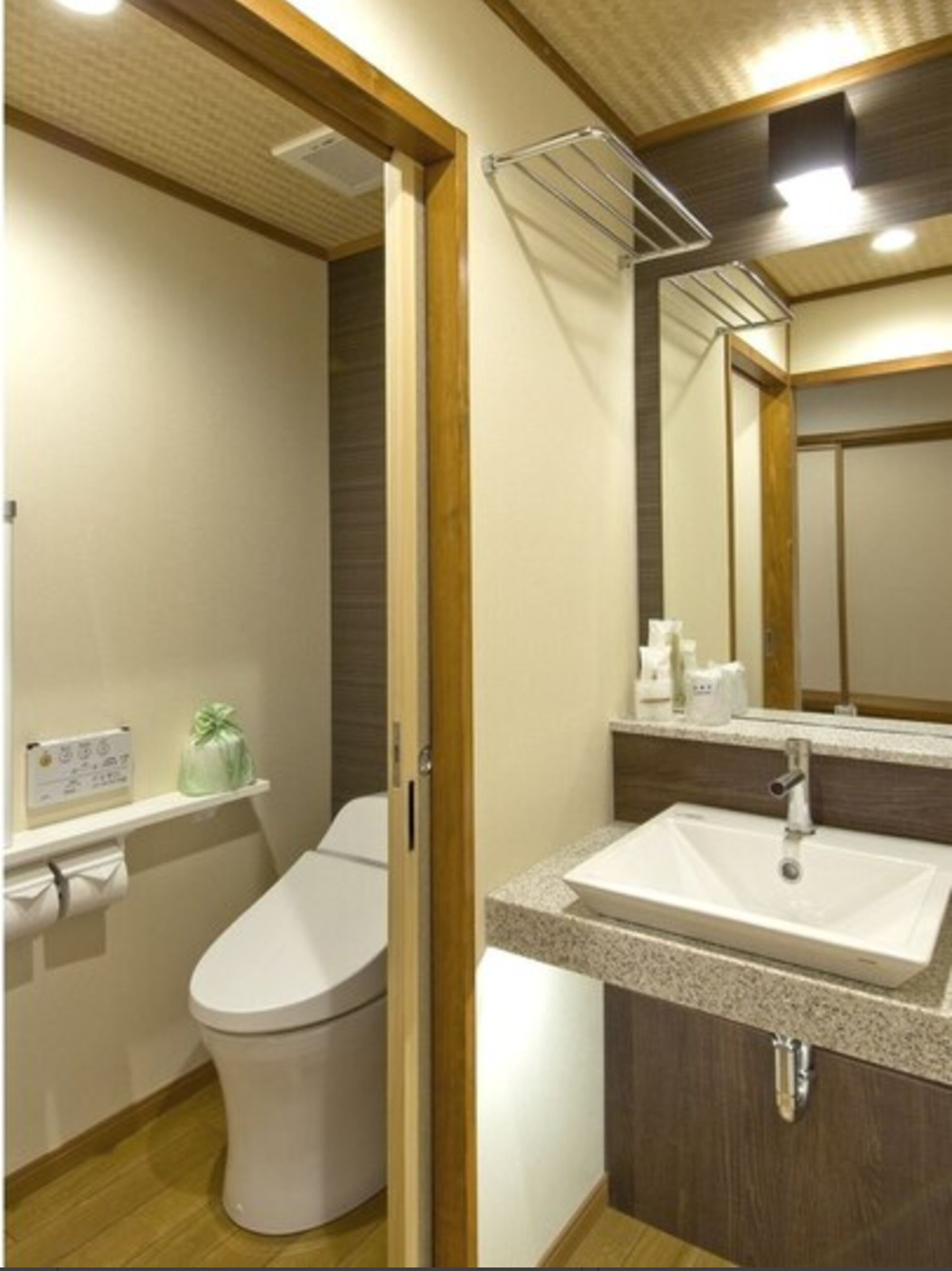 A bathroom with a toilet, sink, and mirror.