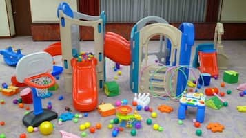 A play area with a basketball hoop, slide, and various toys scattered around.