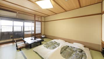 Une pièce de style japonais traditionnel, avec un sol recouvert de tatamis, une petite table basse avec un coussin et un lit doté de draps à motifs.