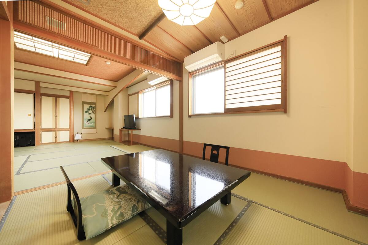 Habitació japonesa tradicional amb fons de tatami, una taula baixa i portes corredisses.