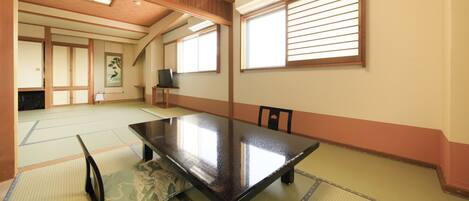 A traditional Japanese room with tatami flooring, a low table, and sliding doors.