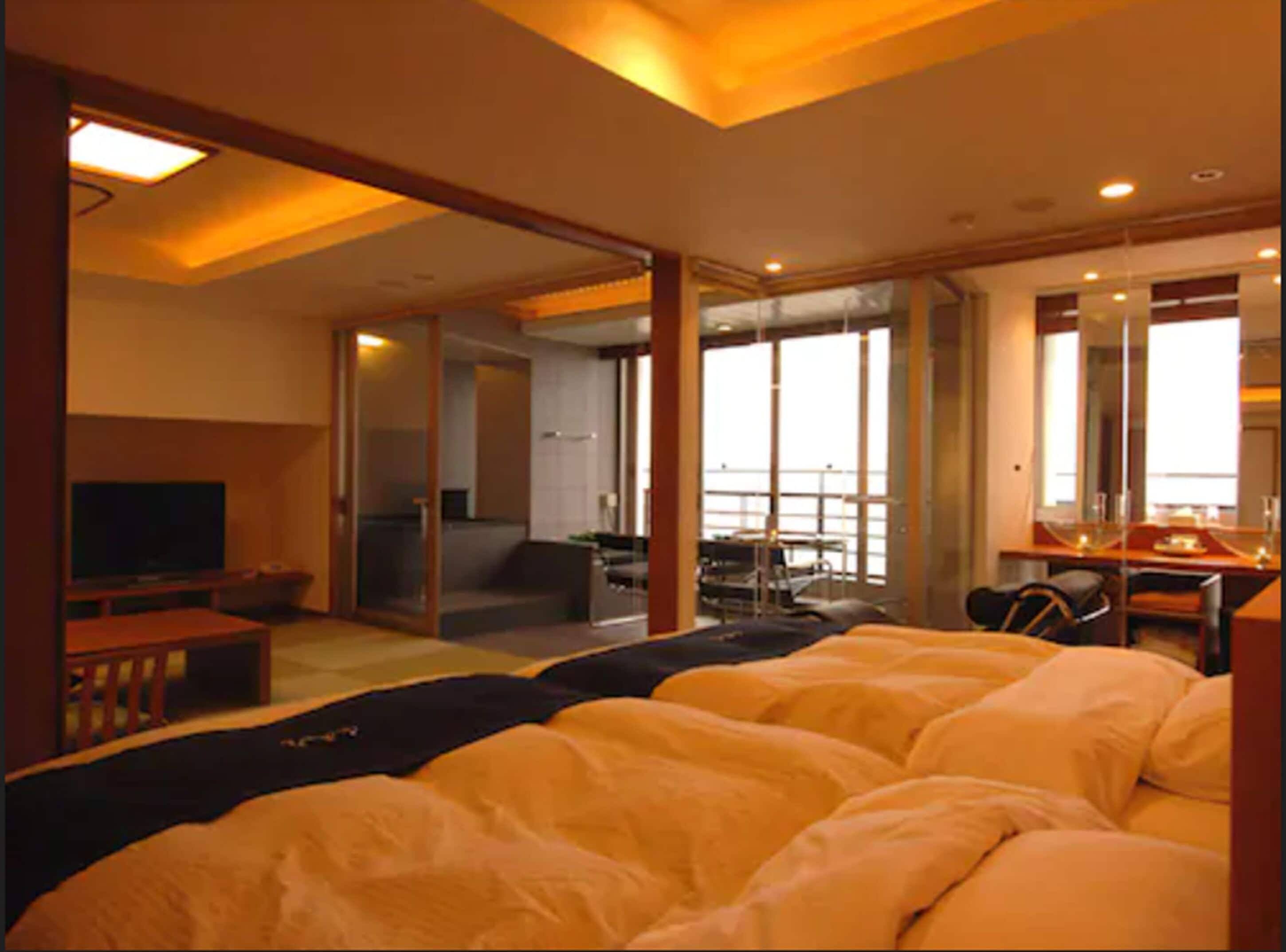 Habitación de hotel con cama, escritorio, televisor y balcón con vistas.