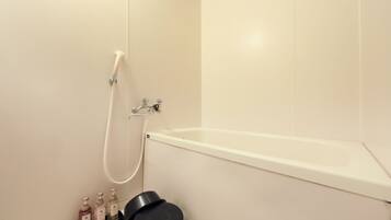 A bathroom with a bathtub, a shower, and a shelf with toiletries.