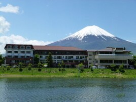 A hotel with multiple floors, a flat roof, and a view of a snow-capped mountain in the background.