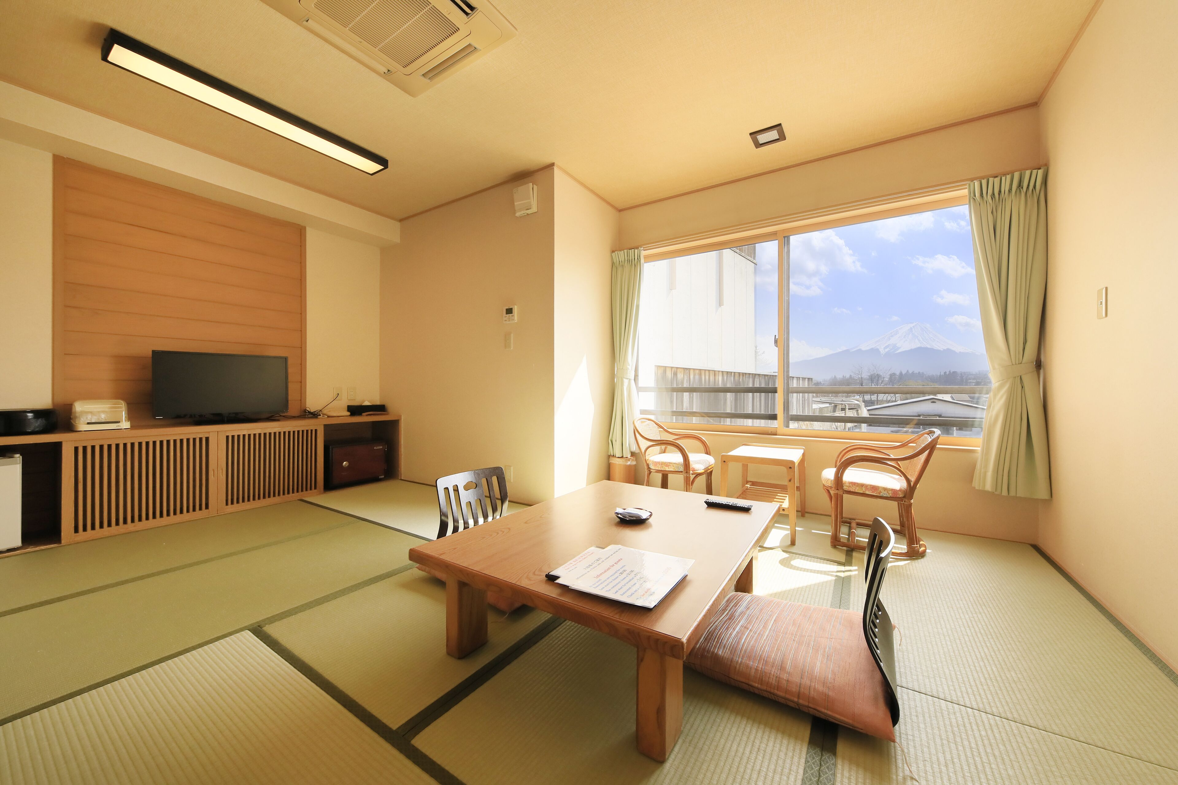A traditional Japanese-style room with tatami flooring, a low table, and a television on a wooden cabinet.