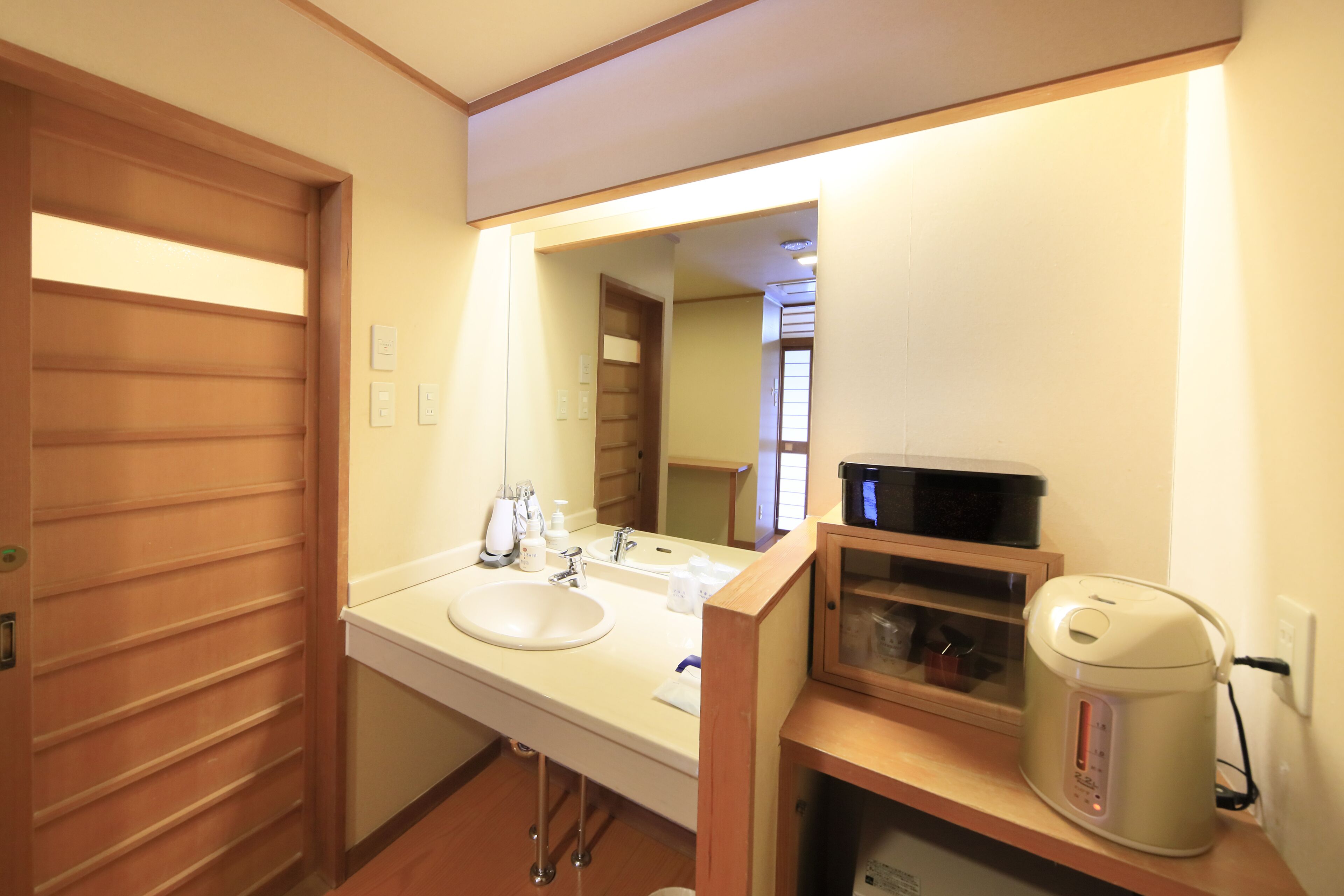 A hotel bathroom with a sink, mirror, and a coffee maker on the countertop.