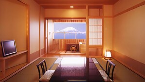 A traditional Japanese-style room with tatami flooring, a low table, and a television on a shelf. - Lakeland Hotel Mizunosato (Fujikawaguchiko)