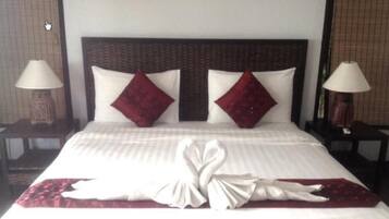 Quarto de hotel com uma cama grande, duas almofadas vermelhas e uma decoração de toalhas em formato de cisne.