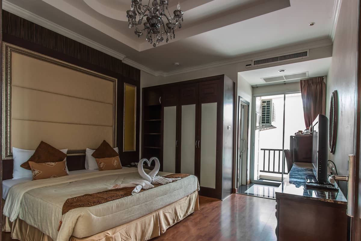 Un dormitorio amplio con una cama grande, piso de madera, candelabro y armario.