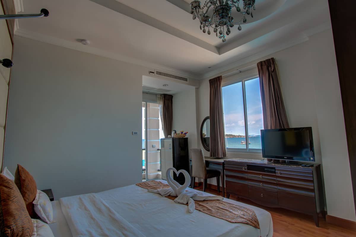 Una habitación de hotel con cama, escritorio con televisor, cómoda y vista al mar.