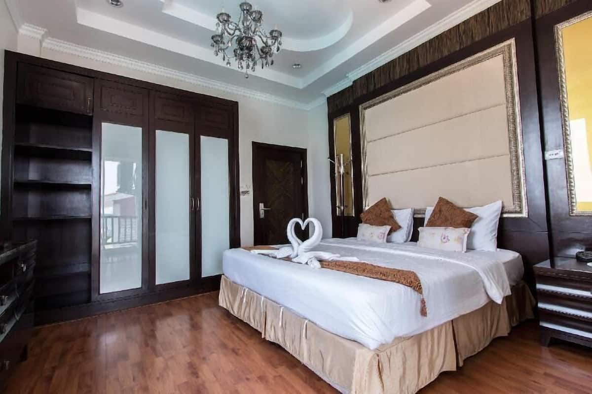 Una habitación de hotel con una cama grande, una araña, un armario y un espejo.