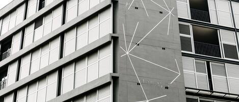 Um edifício de vários andares com design arquitetônico moderno, apresentando uma fachada com padrões geométricos e varandas.