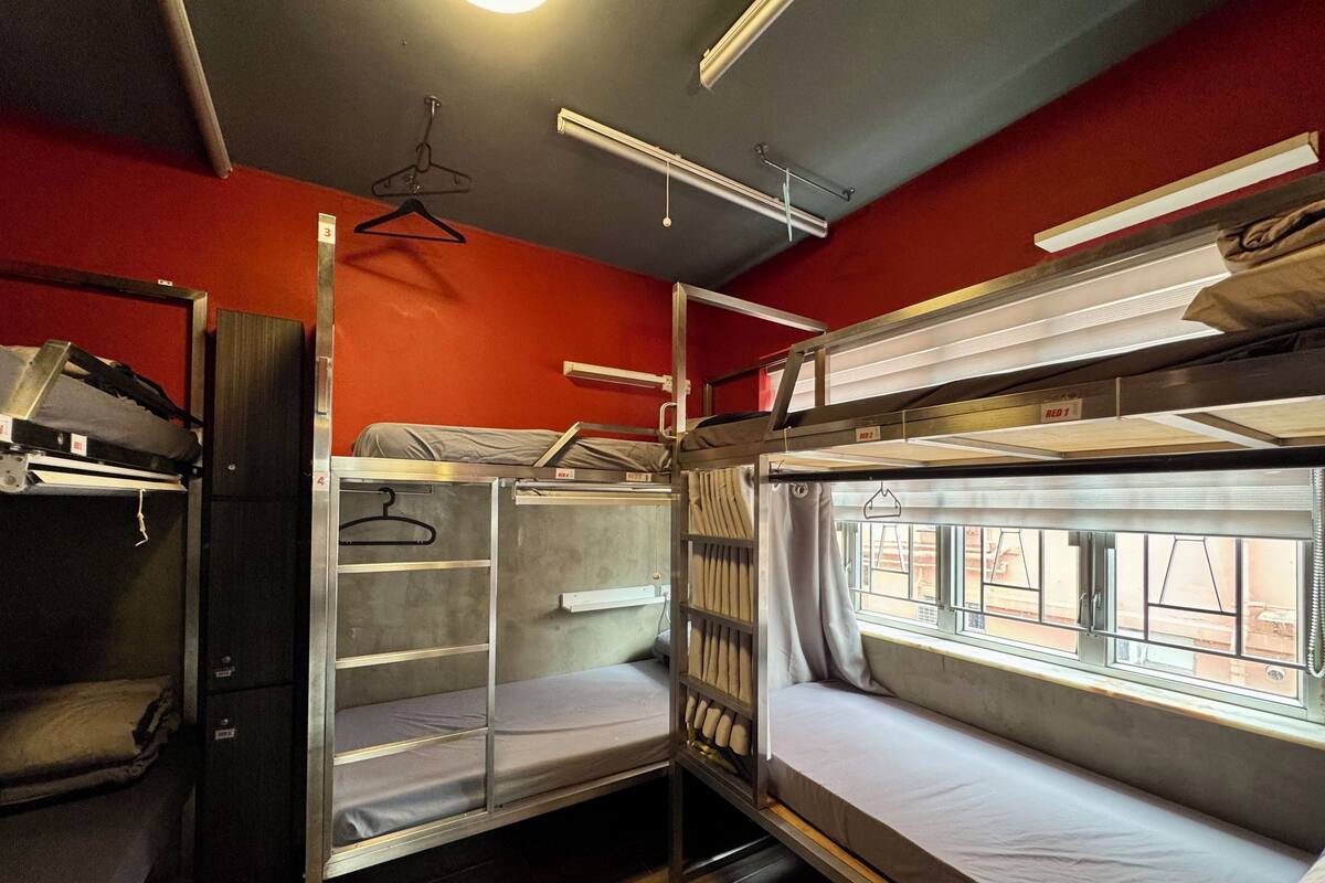 A bunk bed room with a window, a hanging rack, and a shelf unit.
